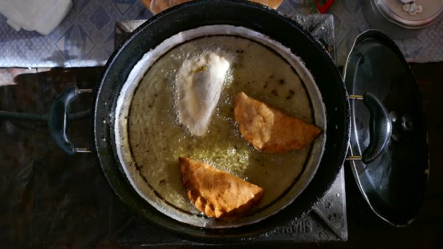 Top view of a pan full of oil preparing and cooking samosa traditional food