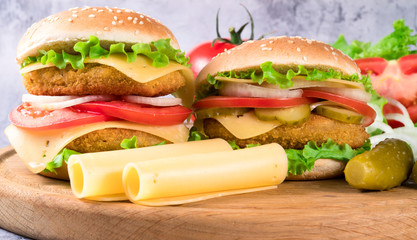 .two burgers on a wooden board