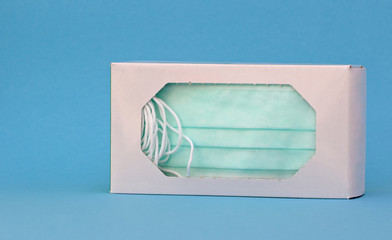 Medical masks or protective masks are in the packaging and ready to use. Light blue background.