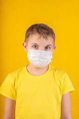preteen handsome boy in protective mask on a yellow background