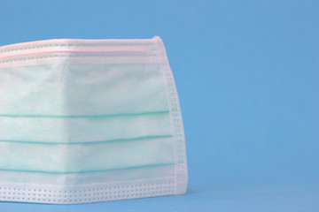 Single medical mask or protective mask stands on light blue background.