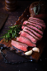 Sliced medium rare grilled beef steak with salt, rosemary and garlic