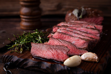 Sliced medium rare grilled beef steak with salt, rosemary and garlic