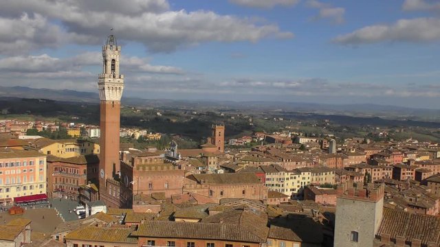 Italy. Warm sunny winter day. The view from the height of the tower Torre del Mangia (literally - the Tower of the Devourer) against the background of a cloudy sky. 