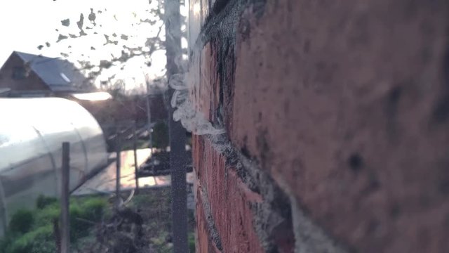 A bullet or projectile hits a brick or wooden wall, and ammunition ricochets off the wall with flying fragments in slow motion