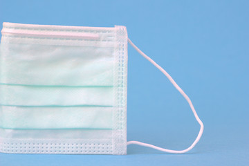 Single medical mask or protective mask stands on light blue background.