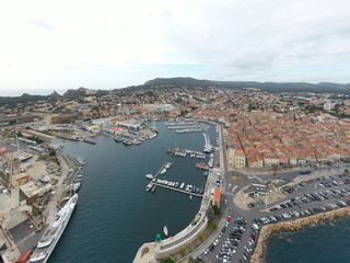 Fototapeta premium Aerial view of sea dry dock in La Ciotat city, France, the cargo crane, boats on repair, a luxury sail yacht and motor yacht, mountain is on background, shipyard
