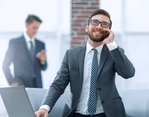 Confident young man talking on phone in office