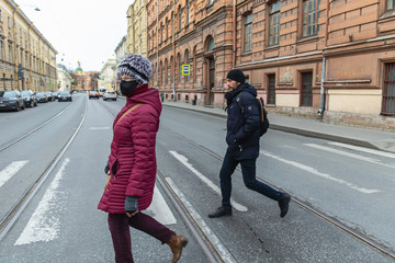 Young woman in mask and man crosses the road. Empty streets in the centre of the city on 1st day of self isolation