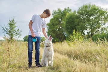 Naklejka na ściany i meble Outdoor portrait of boy teenager with white dog