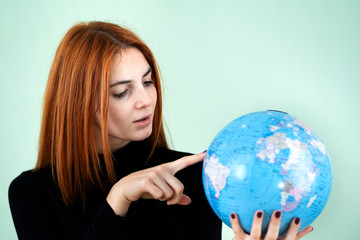 Portrait of a happy young woman holding geographic globe of the world in her hands. Travel destination and planet protection concept.