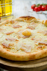 Carbonara pizza with bacon on white wooden table