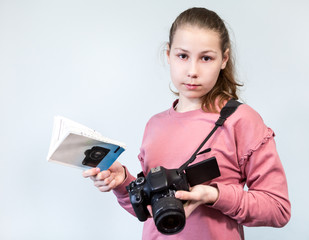 Teenage girl holding DSLR camera and reading operation manual book, learning photography