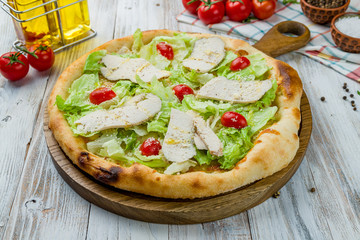 Pizza Caesar on board on white wooden table
