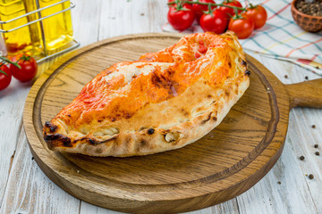 Closed calzone pizza on white wooden table
