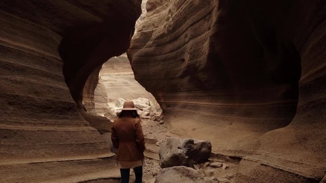 "Woman walking inside in ravine with big stones