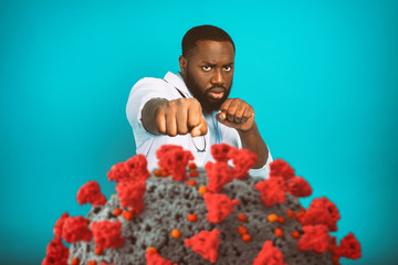Doctor fighting with bare hands against a big virus on cyan background