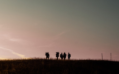 bunch of friends on top of the hill during sunset silhouette
