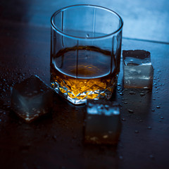 glass of water on blue background with ice whisky and gin