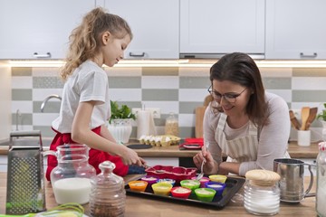 Mothers day, mother and daughter child 9, 10 years old preparing cupcakes