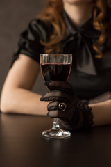 woman's hand in lace glove holds a glass with red wine