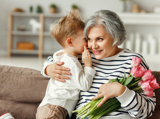 Little boy congratulating grandmother with flowers.