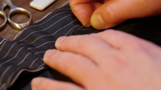 tailoring tradition : professional motion of young tailor hand sewing with a needle and thread by hand according to the ancient tradition