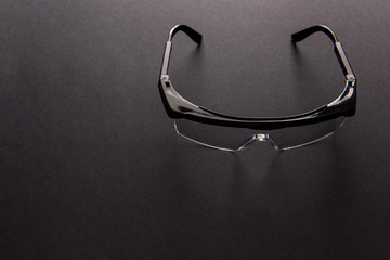 Transparent safety goggles on dark gray background