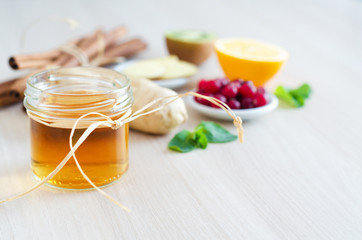food for healthy and Immunity boosting with vitamin C, honey, lemon, cranberries, kiwi, cinnamon, ginger root on light wooden background, copy space. prevention and treatment of colds