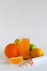 vitamin C pills in container isolated on white background, fresh oranges and apples. Whole fruits with slice of orange on white table. vitamin C to strengthen the immune system. Healthy lifestyle.