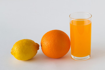 glass of fresh orange juice and orange with yellow lemon on the white background. whole citrus fruit on white table. vitamin C to strengthen the immune system. Healthy lifestyle. copy space.