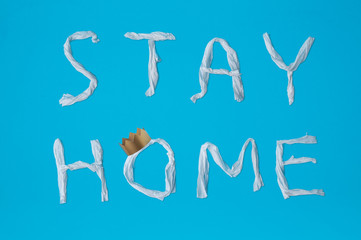 Words stay home made of toilet paper and gold corona on blue background. Epidemic, social isolation, coronavirus COVID-19 concept