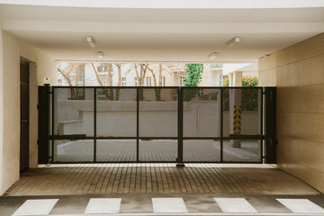 Photo of metalic black moving gate in a building gateway, safe entrance. No one in the yard.