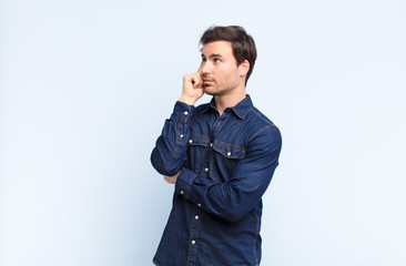 young handsome man with a concentrated look, wondering with a doubtful expression, looking up and...