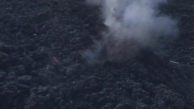Explosion on the surface of the earth from an explosive device, hit by a shell or ammunition, the texture of smoke and flying soil from the shock wave in slow motion, the soil during combat