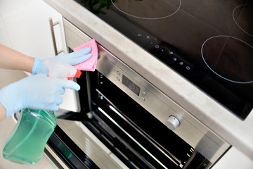 Woman in gloves cleaning kitchen. - obrazy, fototapety, plakaty