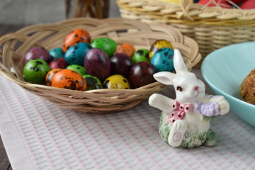 A basket of Easter eggs on the table. Rabbit on the table