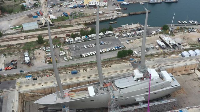 Aerial view of sea dry dock in La Ciotat city, France, the cargo crane, boats on repair, a luxury sail yacht and motor yacht, mountain is on background, shipyard