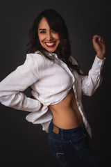 Retrato de mujer casual mexicana alegre posando en fondo gris con blusa blanca