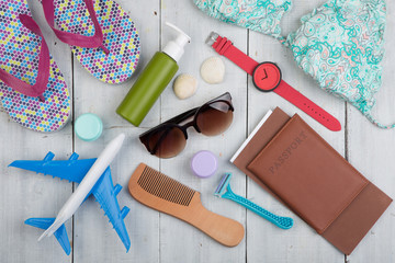 Travel concept - flip flops, swimsuit, sunglasses and over stuff for beach vacation on white wooden background