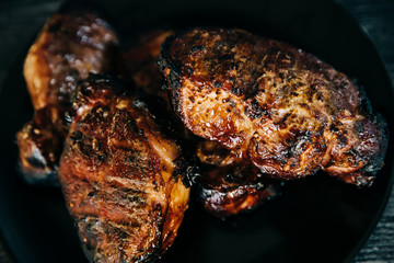 A black plate full of smoked pork chops from an outdoor barbecue grill smoker