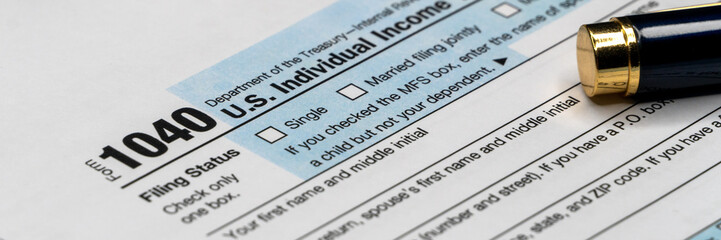 Individual income tax return form, pen and calculator on desk. Tax time