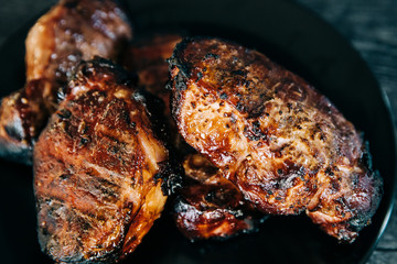 A black plate full of smoked pork chops from an outdoor barbecue grill smoker
