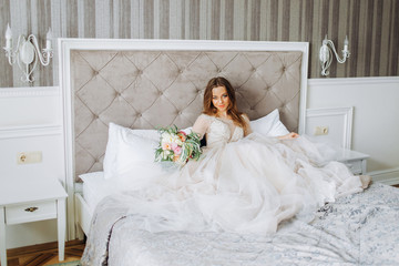 Fototapeta na wymiar Luxury bride sits on a bed in her bedroom. Bride morning.