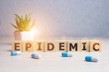 epidemic word written on wood block. epidemic text on wooden table with pills, coronavirus concept...