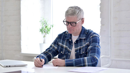Serious Casual Middle Aged Man Doing Paperwork