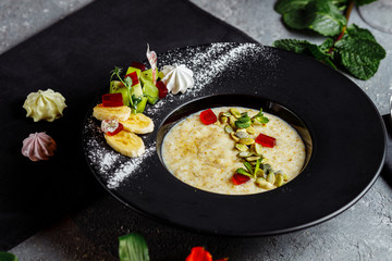 Oatmeal with berries, fruits and marmalade on vintage teal table top view in flat lay style. Hot and healthy breakfast and diet food.