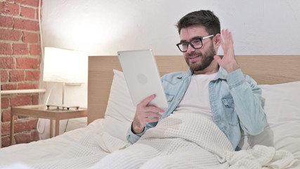 Young Man doing Video Chat on Tablet in Bed