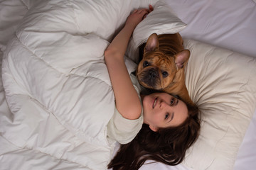 girl and her dog french bulldog sleep in bed