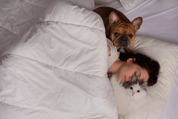 young woman with dog and cat bask in the morning in her bed